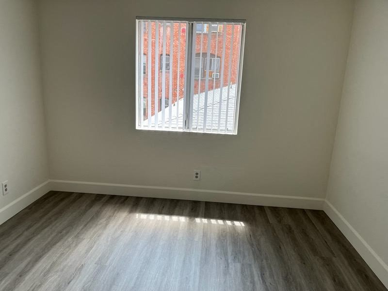 an empty room with wood floors and a window