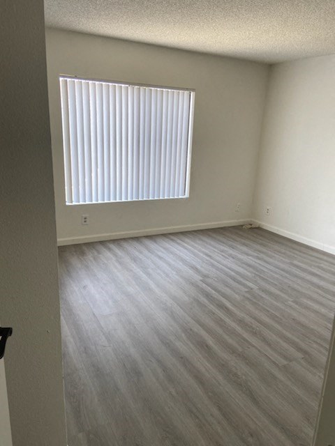 an empty room with a window and wooden floors