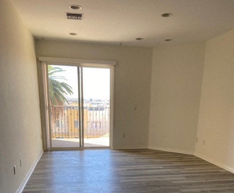 a empty living room with a door to a balcony