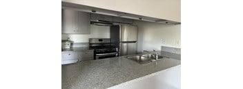 A kitchen with a stainless steel refrigerator and a sink.