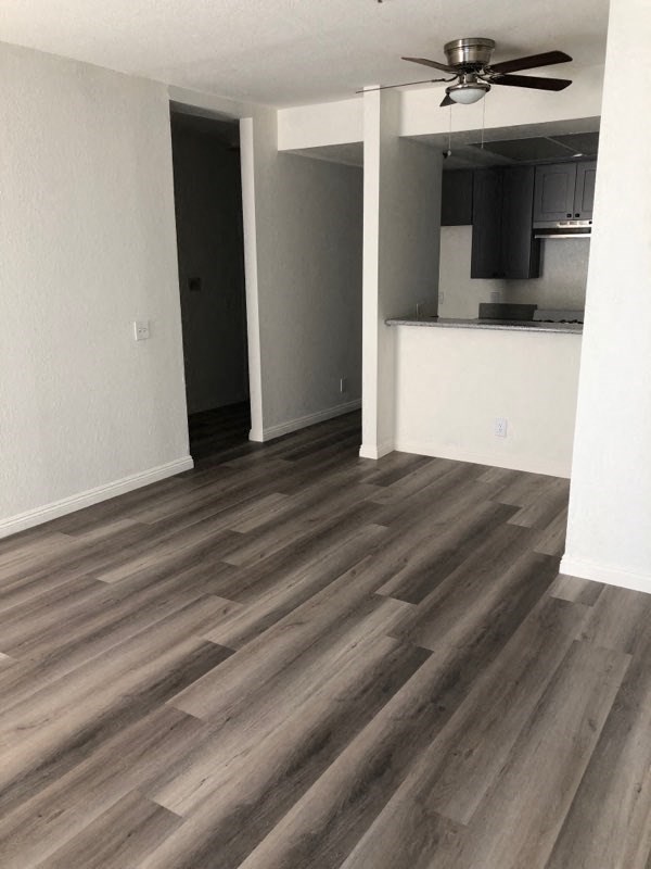 an empty living room with wooden floors and a kitchen