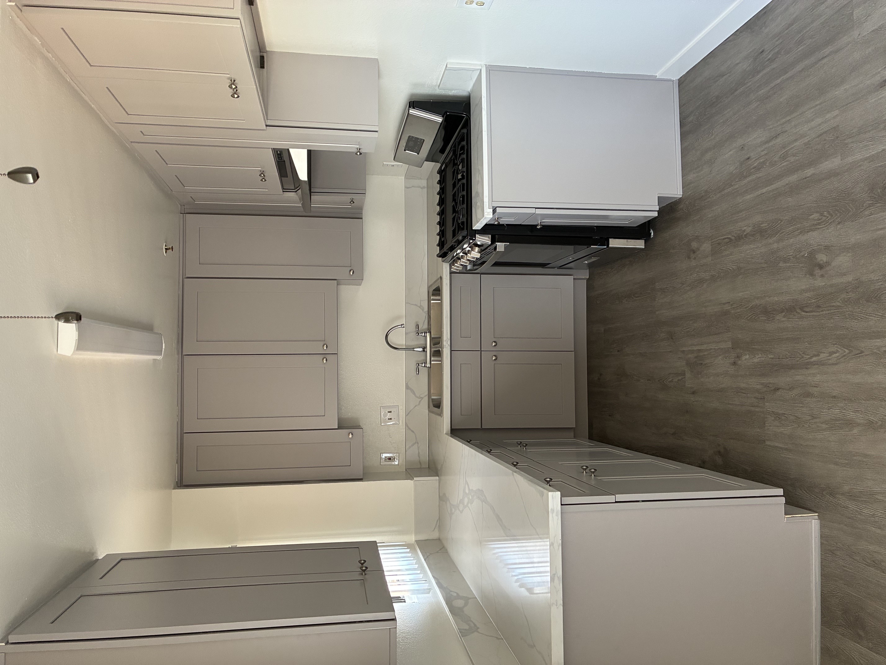 A kitchen with a stainless steel refrigerator and a wall-mounted oven.