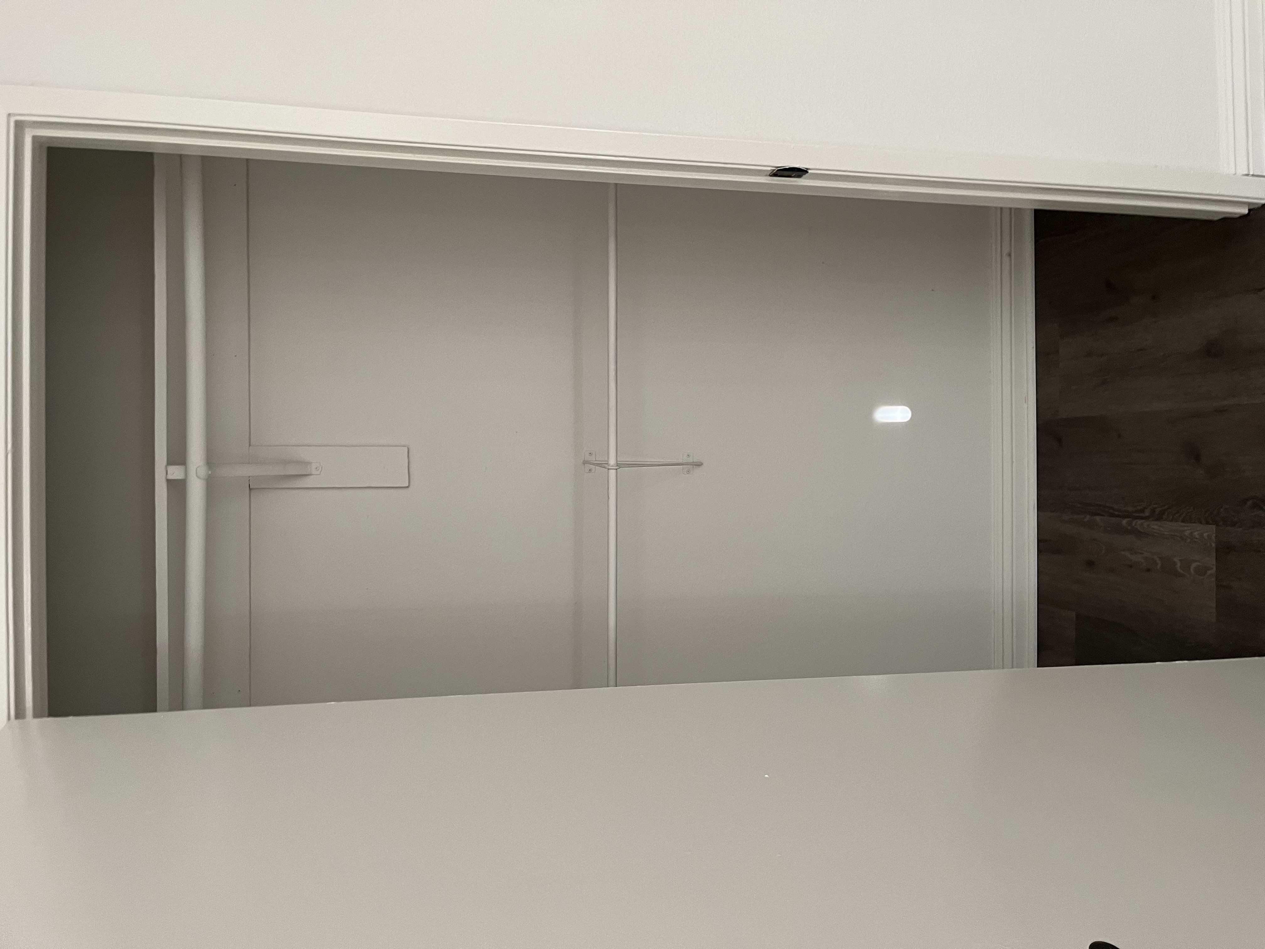 A white cabinet with a glass door and a white countertop.