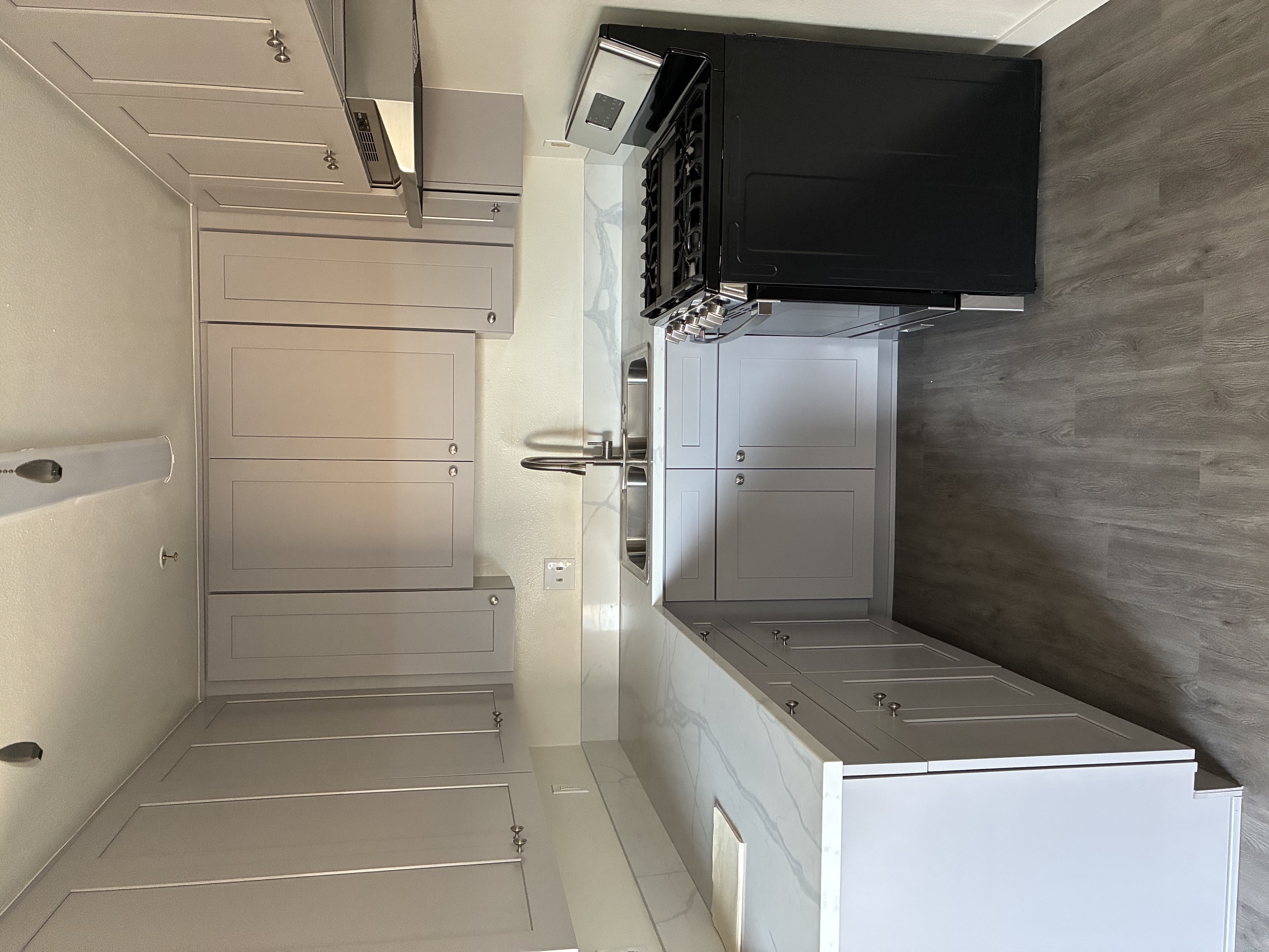 A modern kitchen with a black television mounted on the wall.