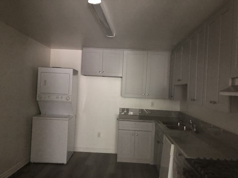 A kitchen with white cabinets and a black counter top.