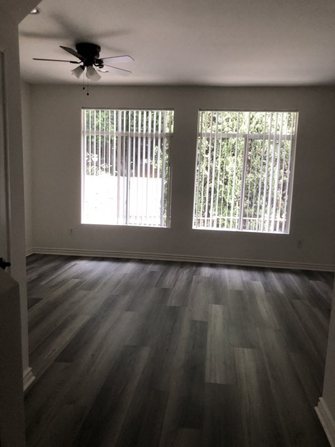 A room with a ceiling fan and two windows.