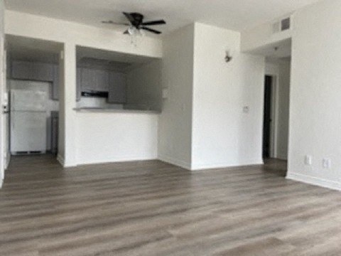 an empty living room with white walls and a ceiling fan
