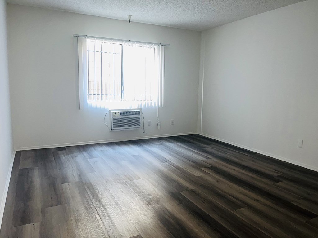 A room with a window and a wood floor.