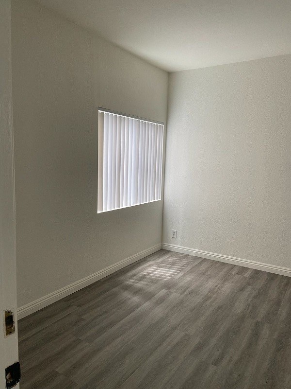 an empty room with a window and wooden floors