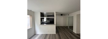 an empty living room with a kitchen and a ceiling fan