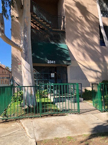 an apartment building with a green awning and a fence