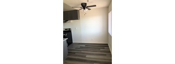 A room with a ceiling fan and a kitchen area.