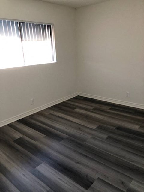 a empty room with a window and wooden floors