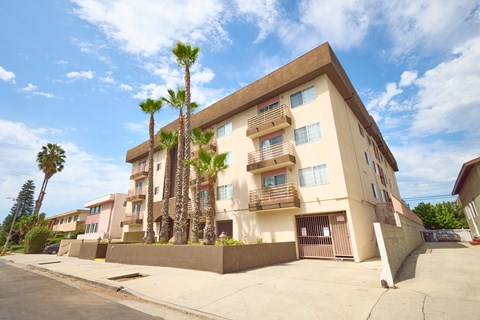 A building with a brown and beige exterior has a balcony on the second floor.