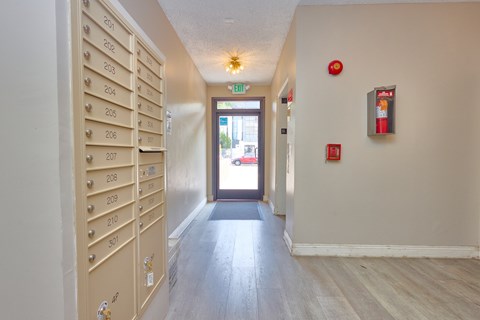 A hallway with a row of mailboxes on the left and a door on the right.