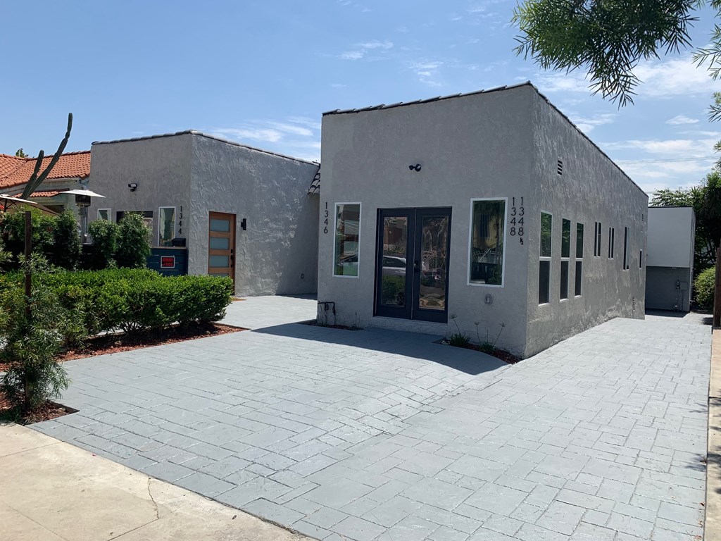 a small white building with a sidewalk in front of it