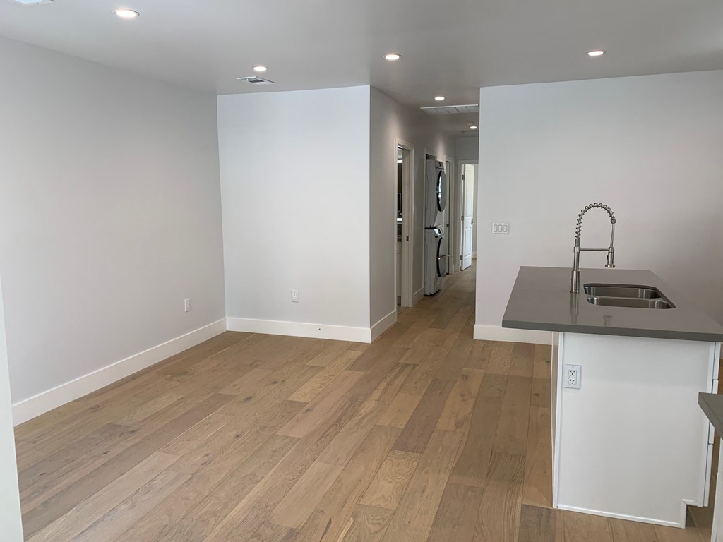 a kitchen and living room with white walls and wood flooring
