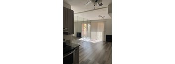A kitchen with a black counter top and wooden floors.