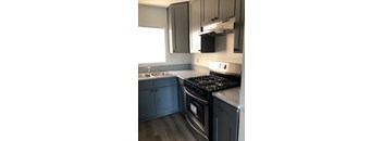 A kitchen with a stove, sink, and cabinets.
