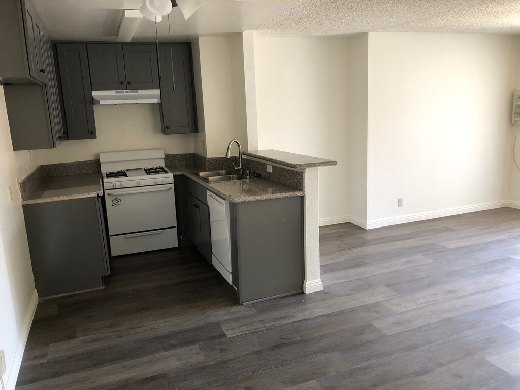 an empty kitchen with stainless steel appliances and a wooden floor