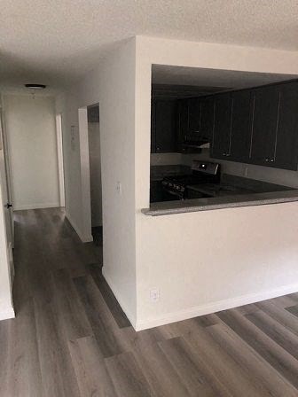 an empty kitchen with black cabinets and a wooden floor