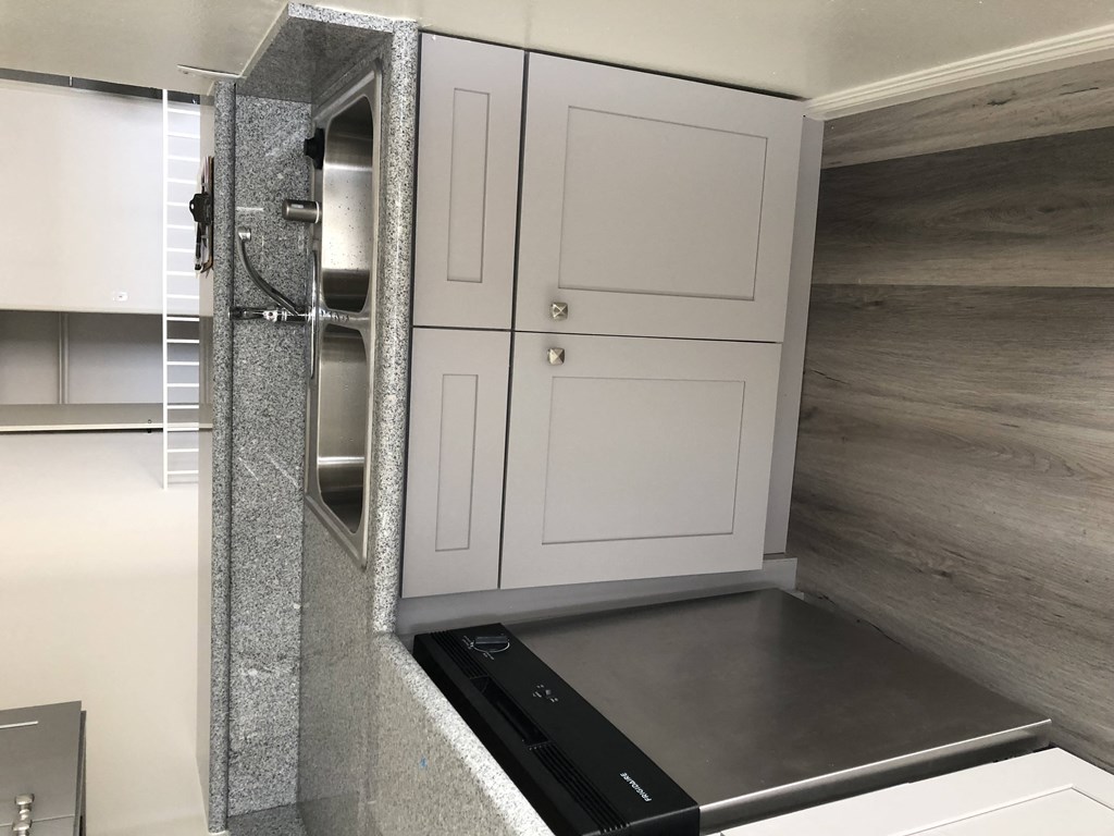 a kitchen with white cabinets and a black stove and a white door