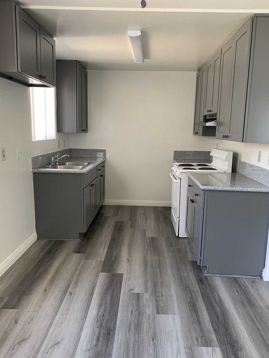 a kitchen with gray cabinets and white appliances and wood flooring