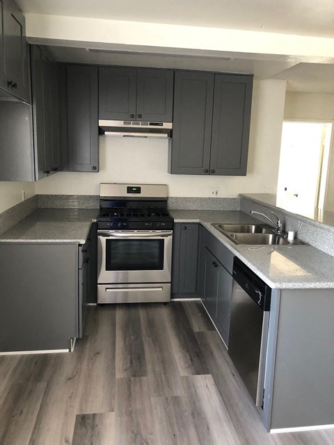 an empty kitchen with stainless steel appliances and gray cabinets