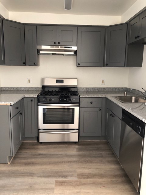 an empty kitchen with black cabinets and stainless steel appliances
