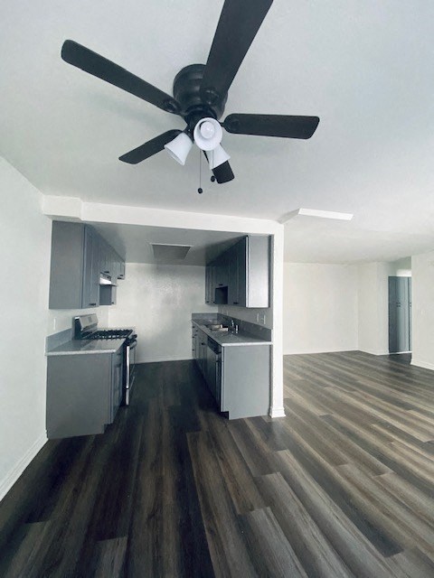 an empty room with a ceiling fan and a kitchen