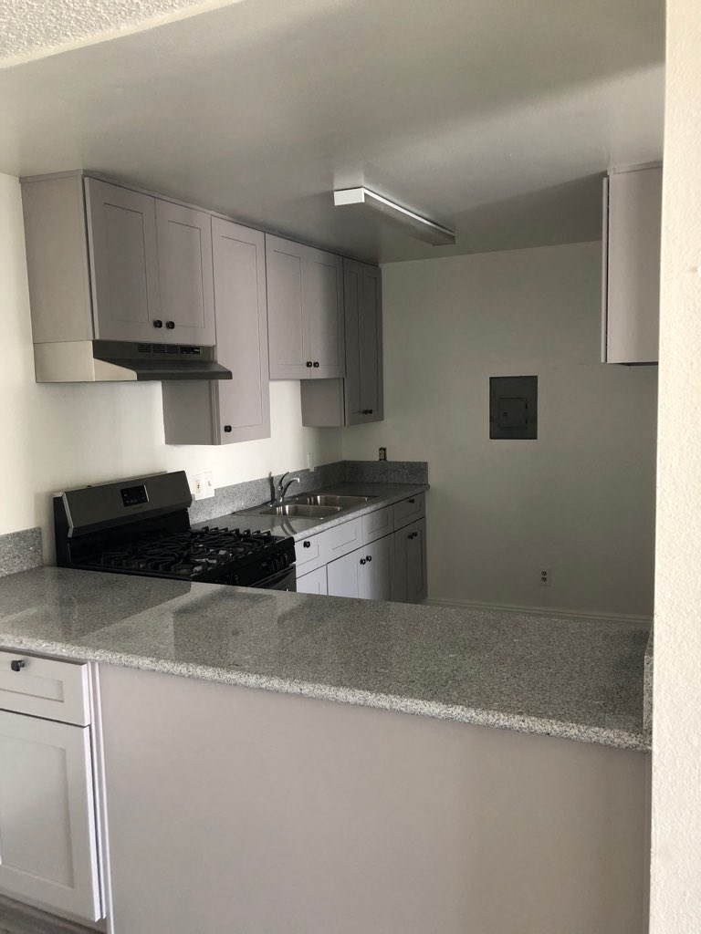 an empty kitchen with white cabinets and a counter top