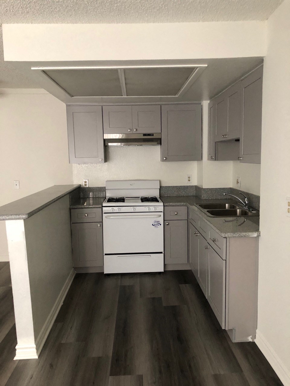 an empty kitchen with white appliances and gray cabinets