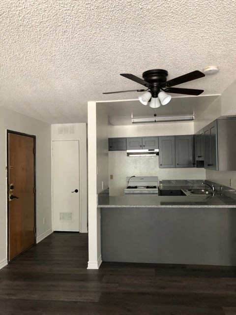an empty kitchen with a ceiling fan and a door