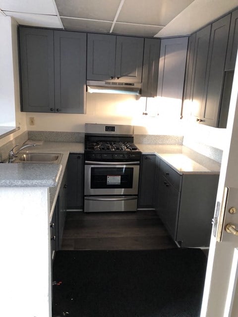 a small kitchen with black cabinets and stainless steel appliances