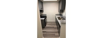 A kitchen with a stove, sink and cabinets.