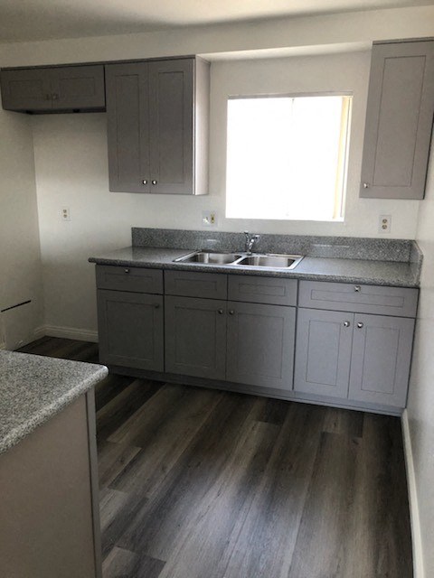 an empty kitchen with gray cabinets and a sink
