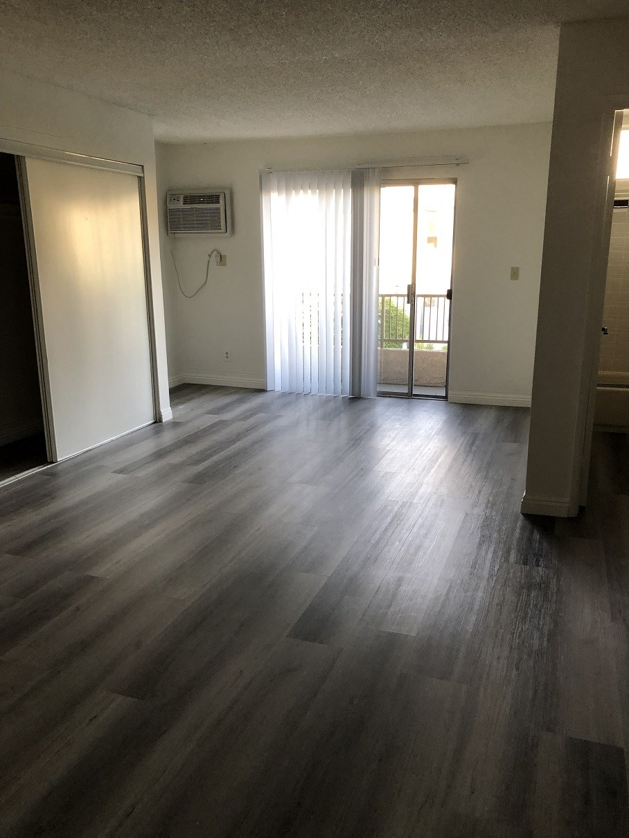 an empty living room with wooden floors and a balcony