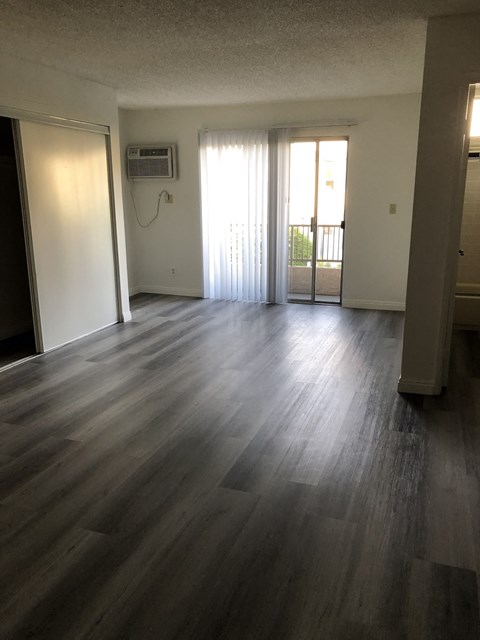 an empty living room with wooden floors and a balcony