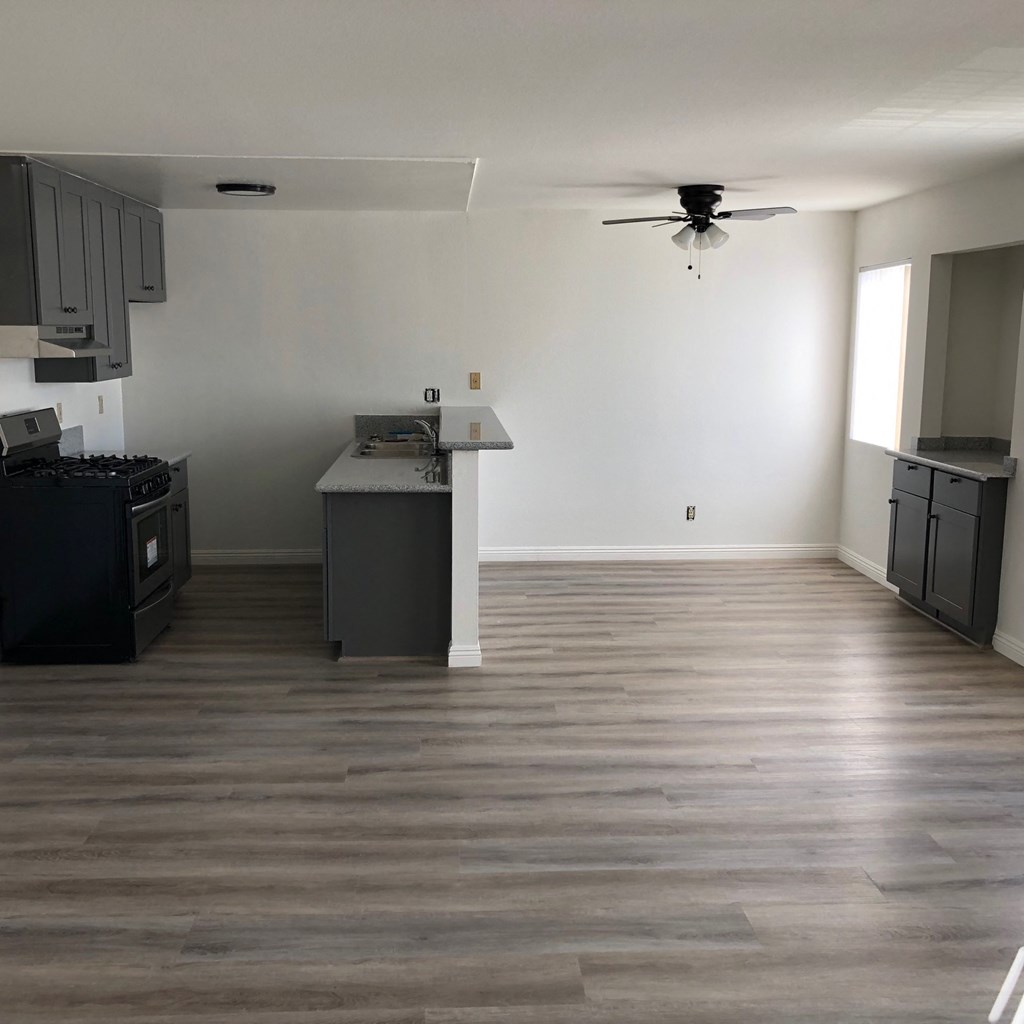 an empty kitchen and living room with wood floors and a ceiling fan
