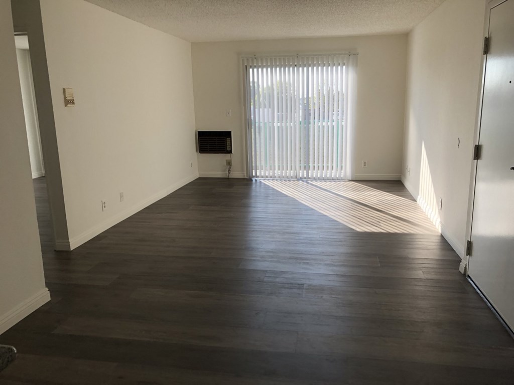 an empty living room with wood floors and a window