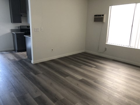 an empty living room with wooden floors and a kitchen