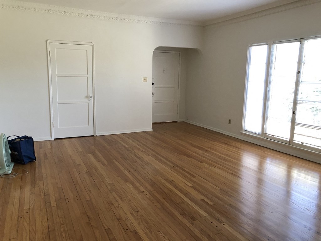 an empty living room with wooden floors and white walls