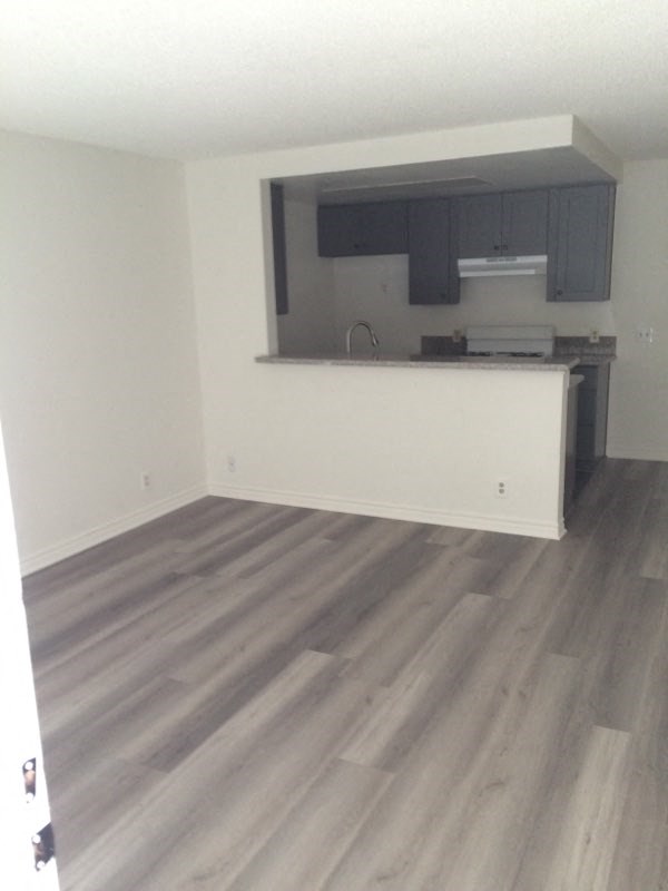 an empty living room with a kitchen in it