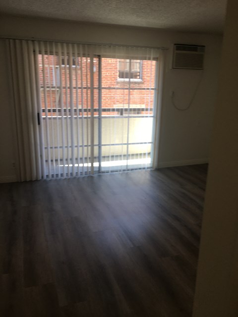 an empty living room with wood floors and a sliding glass door