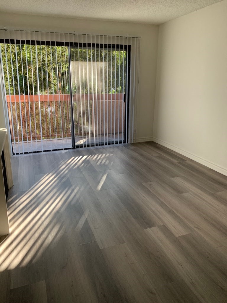 an empty living room with wood flooring and a window