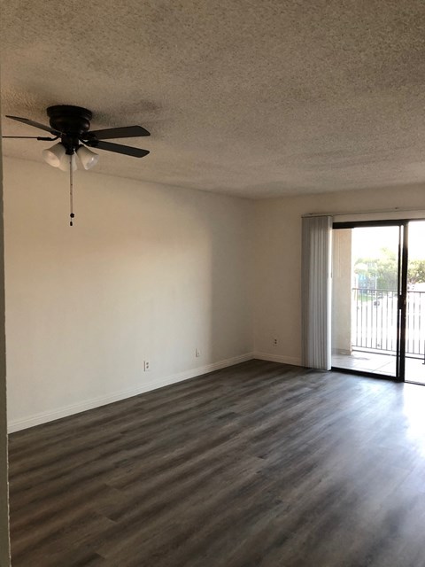 an empty living room with a ceiling fan and a sliding glass door
