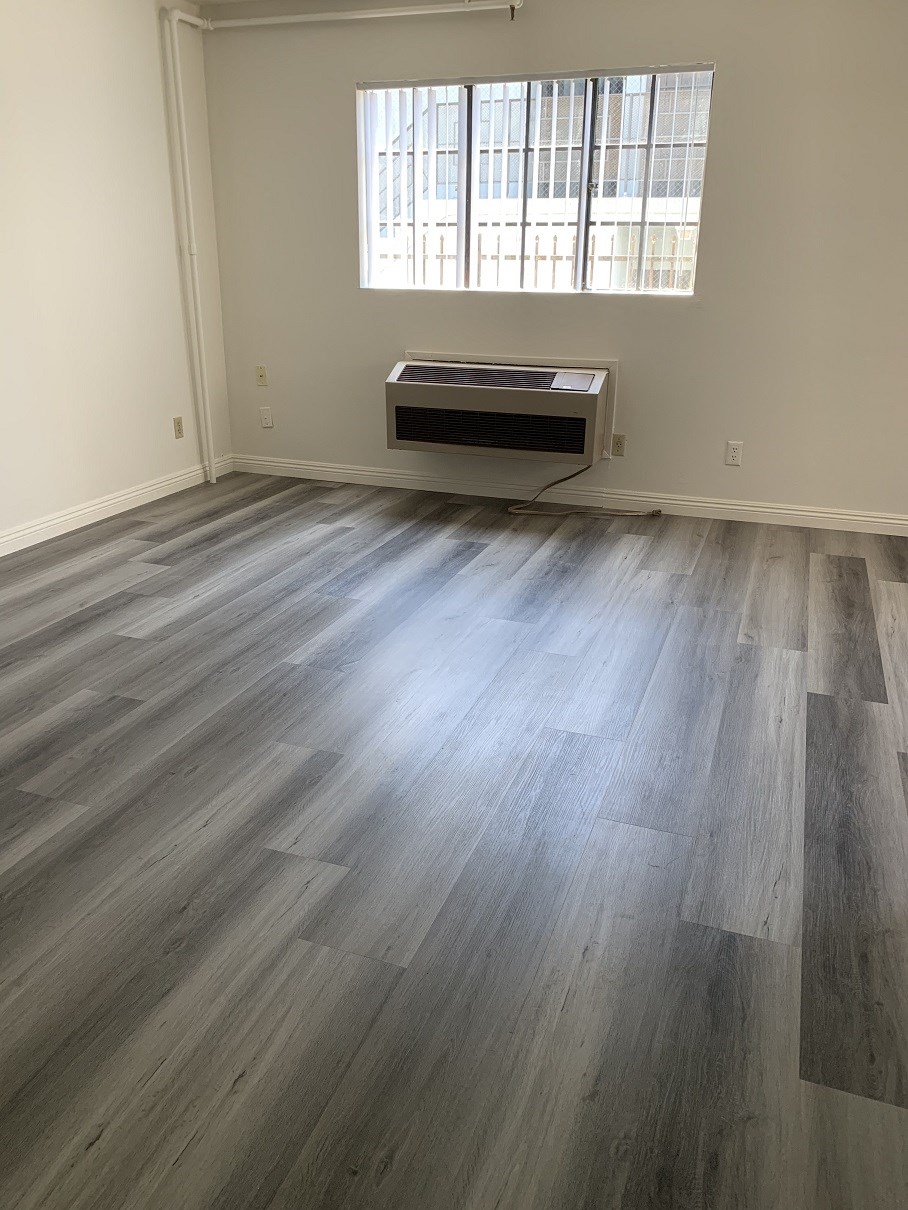 an empty living room with wood floors and a window