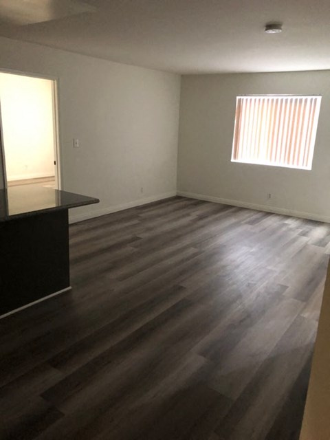 an empty living room with wooden floors and a window