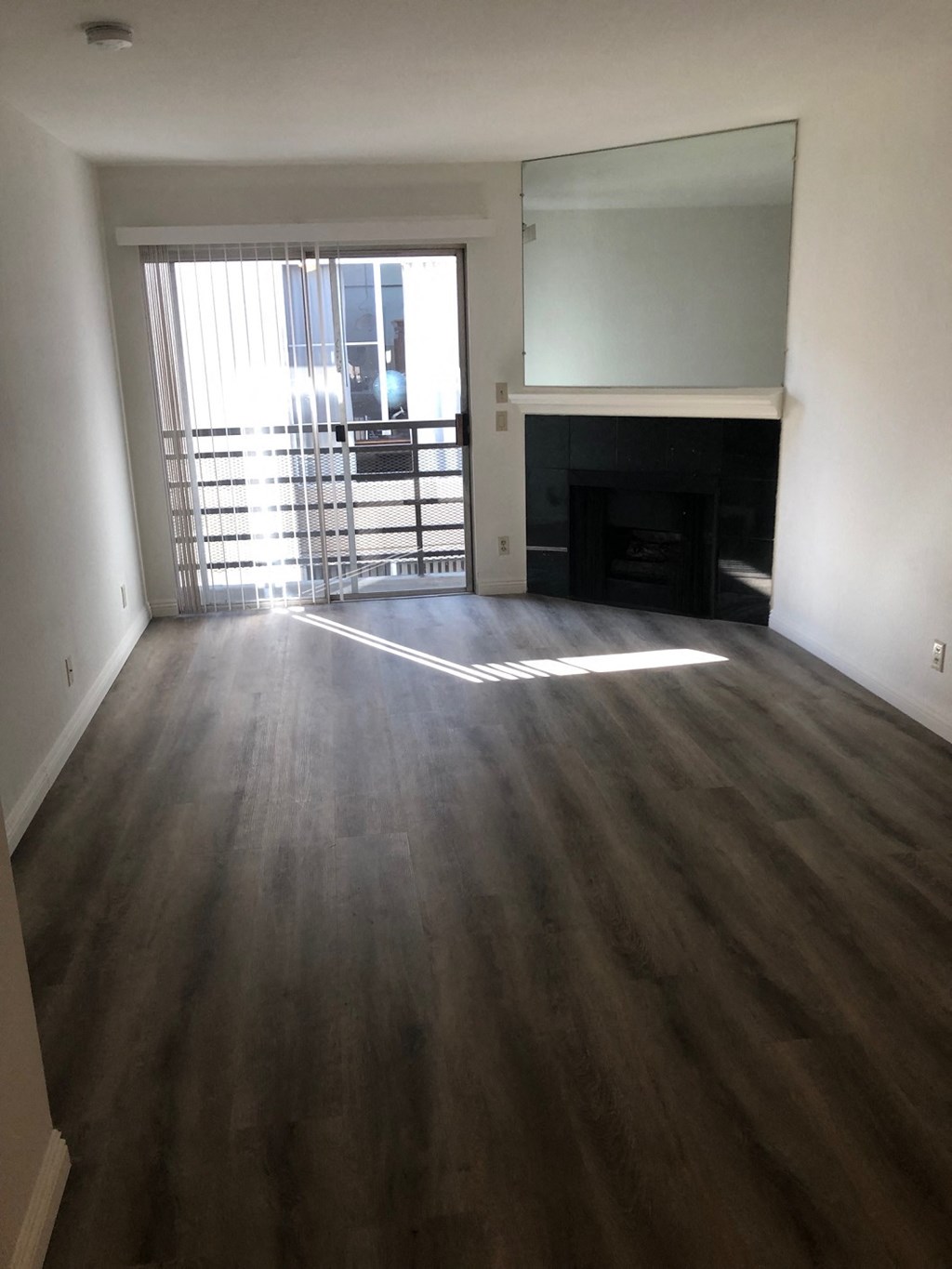 an empty living room with wooden floors and a fireplace