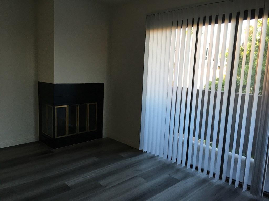 a living room with a large window blinds and a fireplace